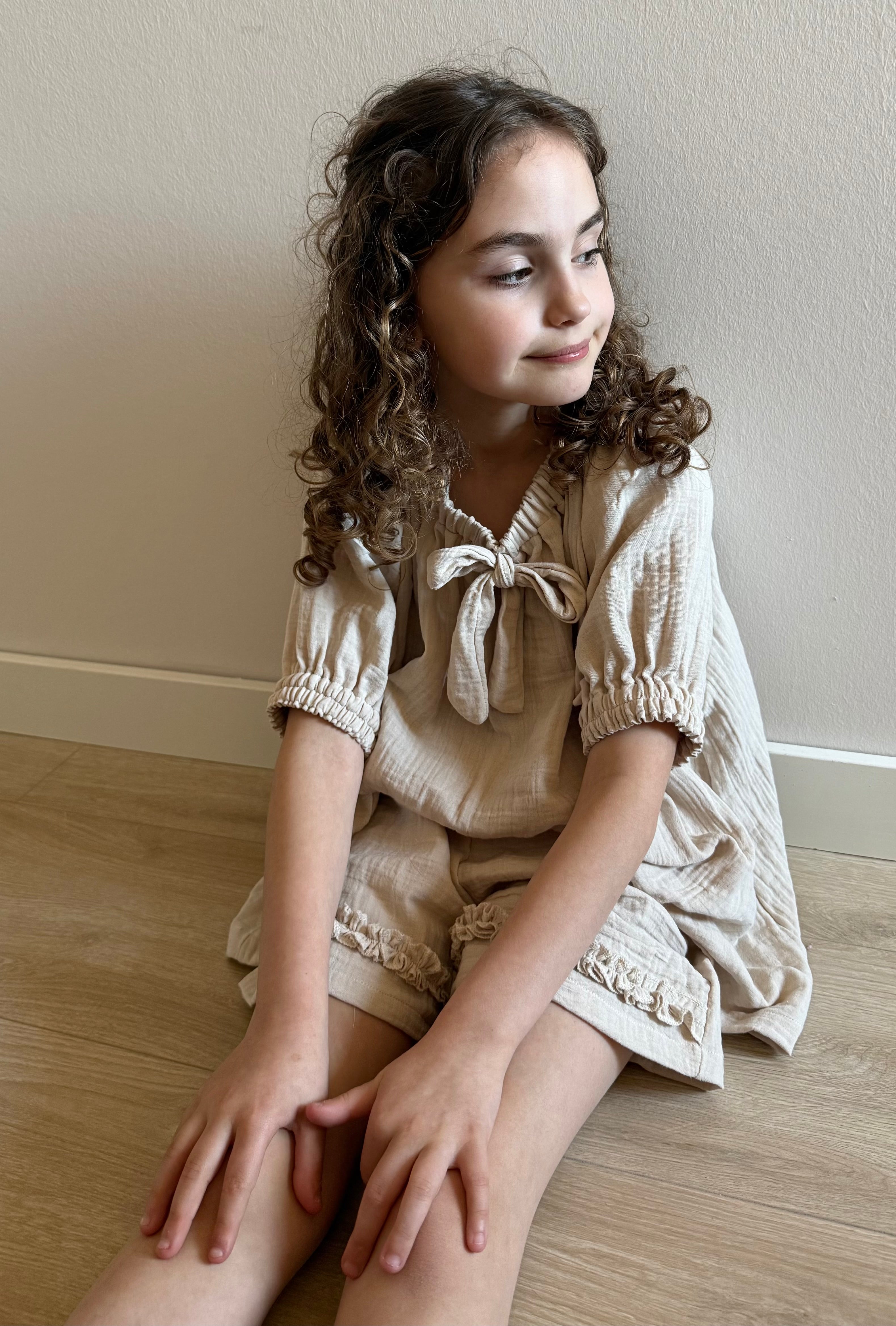 model zittend met mousseline blouse en broekje beige